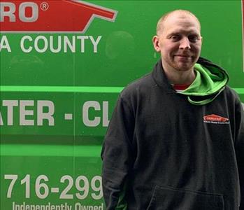 A male employee standing in front of a SERVPRO vehicle. 