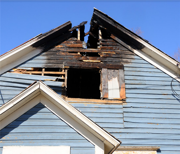 the exterior of a fire damaged home with burnt wooden planks